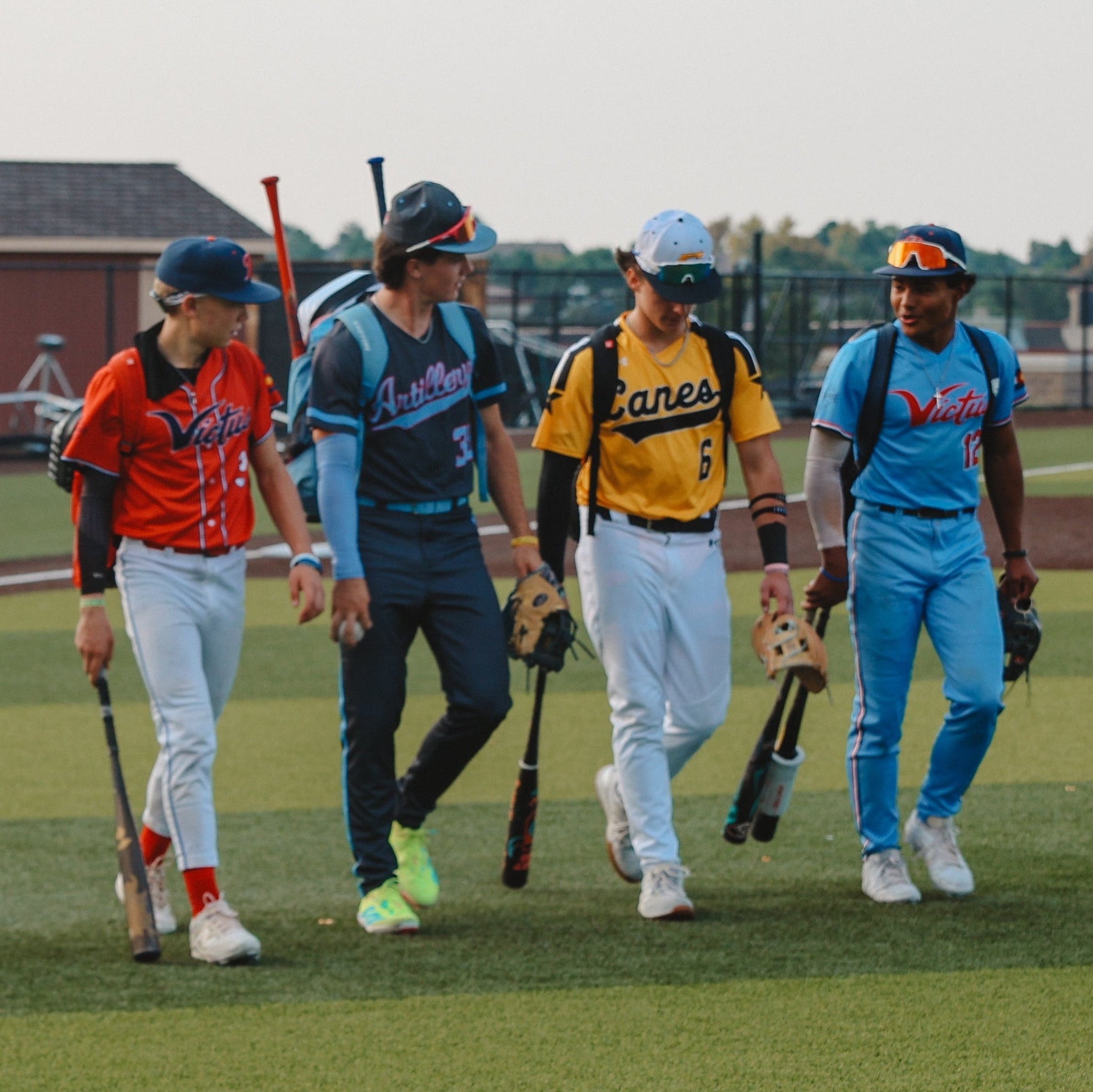 Baseball players walking on a field with bats and gloves